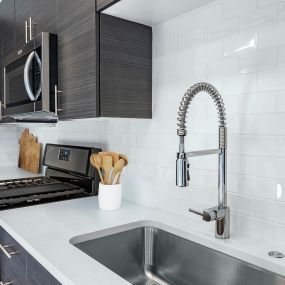 Modern kitchen with white quartz countertops, subway tile backsplash, and stainless steel appliances
