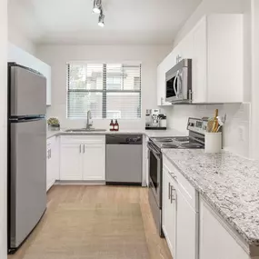 Kitchen with stainless steel appliances, quartz countertops, and white cabinetry