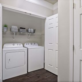 Utility closet with shelving and side by side full size washer and dryer