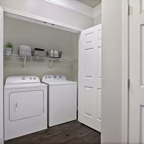 Utility closet with shelving and side by side full size washer and dryer