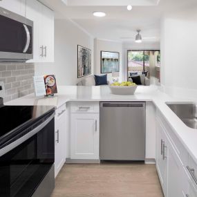 Open concept kitchen with stainless steel appliances and white quartz countertops