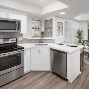 Open-concept windowed kitchen with stainless steel appliances and dining room