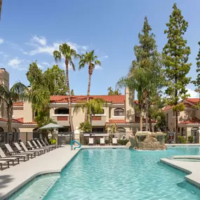 Resort style pool with sundeck surrounded by palm trees