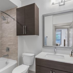 Bathroom with spacious bathtub, tile surround, and curved shower rod at Camden Gallery Apartments in Charlotte, NC