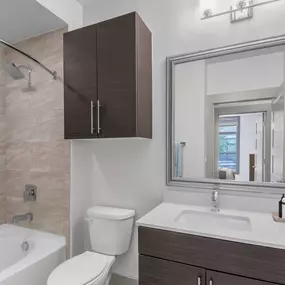 Bathroom with spacious bathtub, tile surround, and curved shower rod at Camden Gallery Apartments in Charlotte, NC