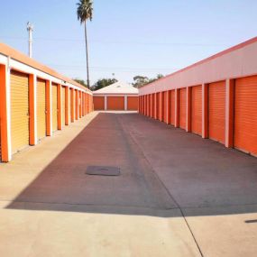wide driveway between two rows of orange storage units