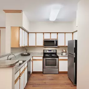 Open and expansive kitchen with stainless steel appliances and wood style flooring