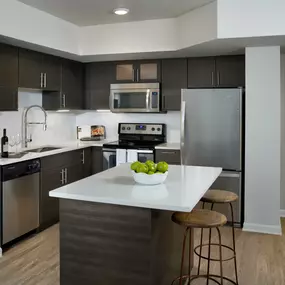 Open-concept kitchen with island and bar seating, stainless steel appliances, and undermount sink