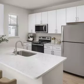 Kitchen with granite countertops, white cabinetry and stainless steel appliances at Camden Spring Creek Apartments in Spring, Texas