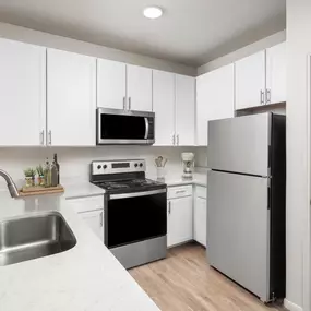 Modern kitchen with stainless steel appliances, white quartz countertops, white cabinetry, undermount sink with pull-down spray faucet at Camden Spring Creek Apartments in Spring, TX