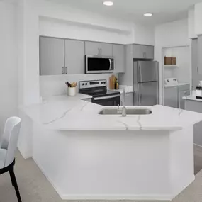 Kitchen with quartz countertops and stainless steel appliances alongside laundry room at Camden Montierra apartments in Scottsdale, AZ