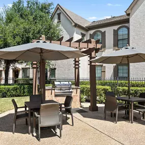 Poolside grills and tables with umbrellas at Camden Brushy Creek apartments in Austin, TX