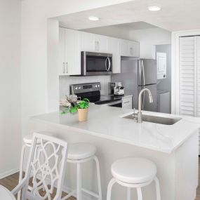 Beautifully renovated apartment featuring Shaker style white cabinetry with satin nickel finish hardware, microwave, ceramic cooktop stove, quartz countertops, glossy white beveled backsplash, one-handle pull-down kitchen faucet.