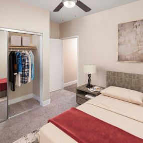 Bedroom with lighted ceiling fan and mirrored closet