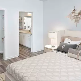 Beautifully renovated bedroom with walk-in closet featuring wood shelves and rods. The bathroom features quartz countertops, curved shower rod, rain shower head, satin nickel fixtures and hardware, and LED vanity lighting.