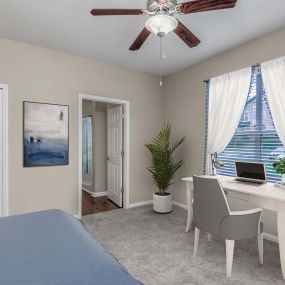 Bedroom with desk area ceiling fan carpet flooring and folding door closet