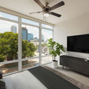 Bedroom with floor to ceiling windows ceiling fan and carpet flooring
