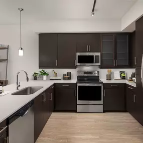 Kitchen with white quartz countertops and stainless steel appliances at Camden Rainey Street apartments in Austin, TX