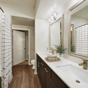 Contemporary-style bathroom with double sink vanity and curved shower rod at Camden Farmers Market Apartments in Dallas, TX