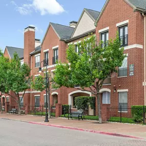 Building exterior showing sidewalk with benches and trees