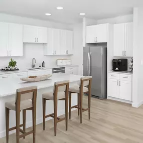Townhome kitchen with white quartz countertops, white shaker cabinets, spacious island, and stainless steel appliances at Camden Farmers Market apartments in Dallas, TX