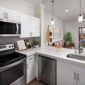 Open-concept kitchen with white quartz countertops, gray subway tile backsplash, and stainless steel appliances