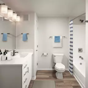 Contemporary bathroom with white quartz countertop, white shaker cabinets, wood-style flooring, and curved shower rod