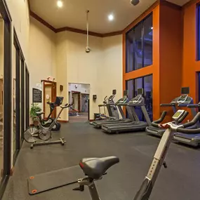 Fitness center with cardio machines and stationary bike under double height ceiling