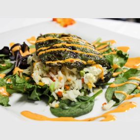 Piment Poblano Farci
Grilled poblano pepper stuffed with goat cheese &vegetable jasmine rice, topped with a spicy aioli and served on a bed of baby spinach with a side of sautéed vegetables.