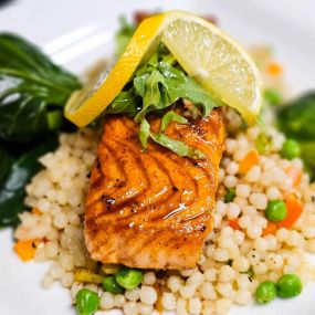 Saumon Glacé au Miel
Pan-seared salmon with honey soy ginger glaze over vegetable cous cous with sautéed vegetables