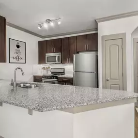 Kitchen with large island, hardwood-style flooring, and undermount sink.