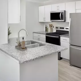 Modern renovated kitchen with white cabinetry and granite countertops at Camden Midtown Atlanta in Atlanta, GA