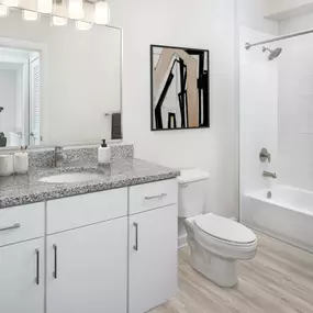 Modern bathroom with hardwood-style flooring, granite countertops, and subway tile surround in bath at Camden Midtown Atlanta in Atlanta, GA