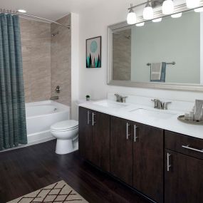 Ensuite with double sink vanity, LED lighting, and curved shower rod all make this bathroom a luxurious space at Camden Boca Raton apartments in Boca Raton, Florida.