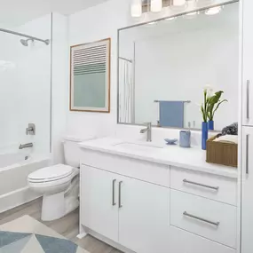 White contemporary apartment bathroom with white quartz countertops and bathtub and shower combination at Camden Grandview in Charlotte, NC