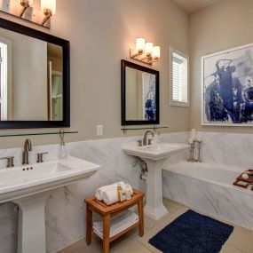 The townhomes bathroom with stand-alone vanities, tile flooring, and a bathtub