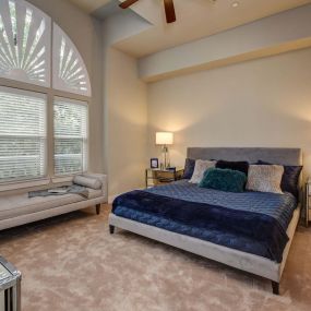 The townhomes bedroom with curved windows, angled ceiling, and ceiling fan