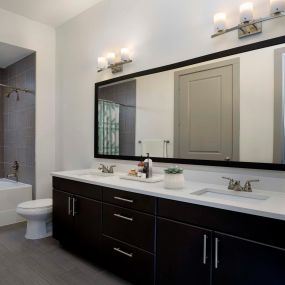 Terrace bathroom with double vanity sinks, espresso cabinets, white quartz countertops,  curved shower rods, and large soaking bathtub and shower combination