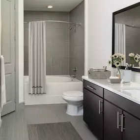 Terrace bathrooms with white quartz countertop, framed mirrors, bathtub and shower combination with curved shower rods and tile surround