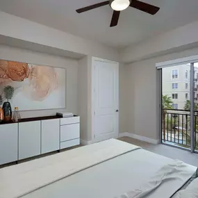 The gallery bedroom with Juliet balcony, carpet flooring, and ceiling fan