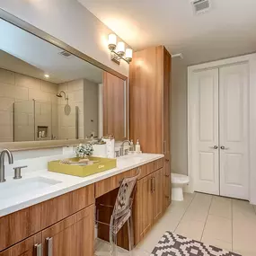 The gallery bathroom with double vanity sinks, a glass-enclosed shower, and an attached closet