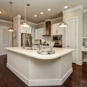 The townhomes kitchen with stainless steel appliances, white quartz countertops and cabinets, curved island, and built-in desk