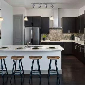 The terrace kitchen with glass cooktop, stainless steel appliances, bar seating, and mosaic tile backsplash