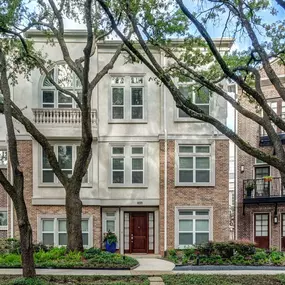 The townhomes building exterior along street lined with large trees