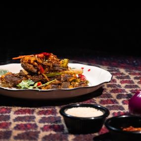 Crispy Lamb Chops in a white round plate on the table at Karamay, London.