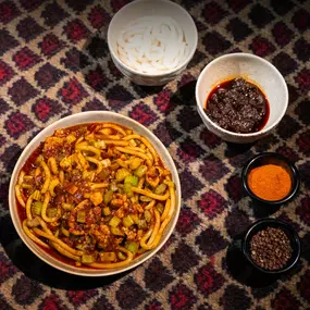 Volcano Rice Noodles served on a white round plate, featuring vibrant colors and spicy aromas with sauces on the side at Karamay, London