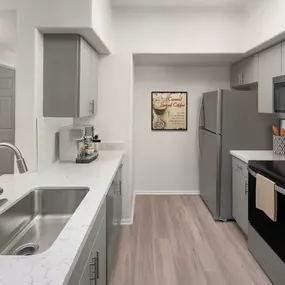 Camden Pecos Ranch Apartment home Chandler Arizona luxury kitchen with wood-like flooring white quartz countertop brushed nickel fixtures and stainless steel appliances