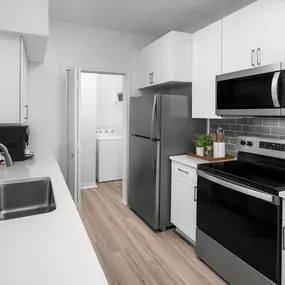 Renovated kitchen with white quartz countertops and white cabinets at Camden Addison apartments in Addison, TX