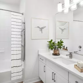 Renovated bathroom with white quartz countertops and white cabinets at Camden Addison apartments in Addison, TX