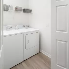 Laundry closet with full-size washer and dryer and built-in wire shelf at Camden Addison apartments in Addison, TX